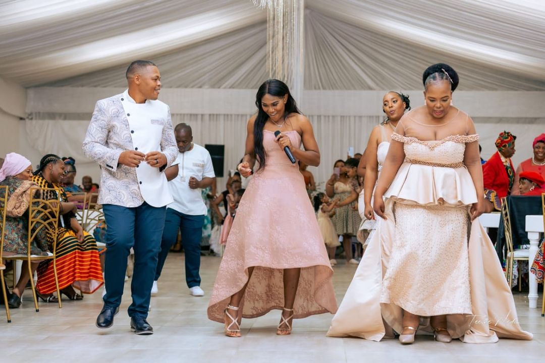 Groom and bride dancing across wedding attendants.